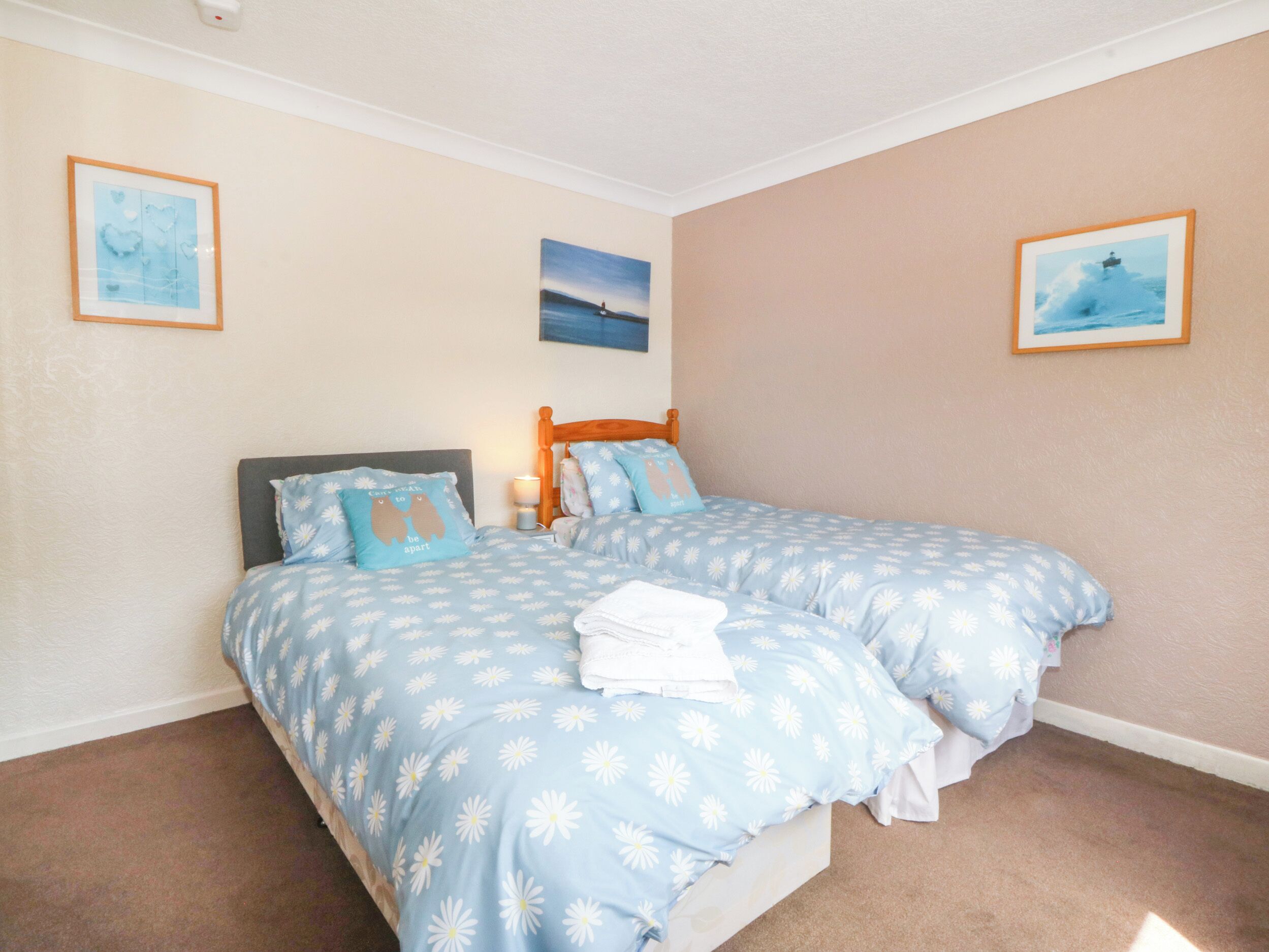 A bedroom with two beds, a wooden headboard, and a nightstand.