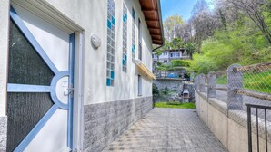 A building with a paved walkway, a door with a blue frame, and a window with a blue tint. - Casa Zaira 1 2BR in Caviano Gambarogno (Gambarogno)