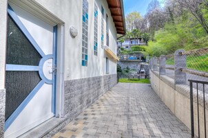 Un edificio con un sendero adoquinado, una puerta con marco azul y un ventanal con tonalidad azulada.