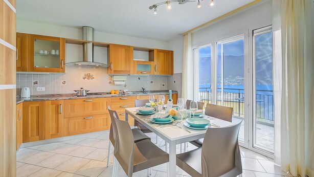 Une cuisine moderne avec des meubles en bois, une table à manger pour quatre personnes et un balcon avec vue.