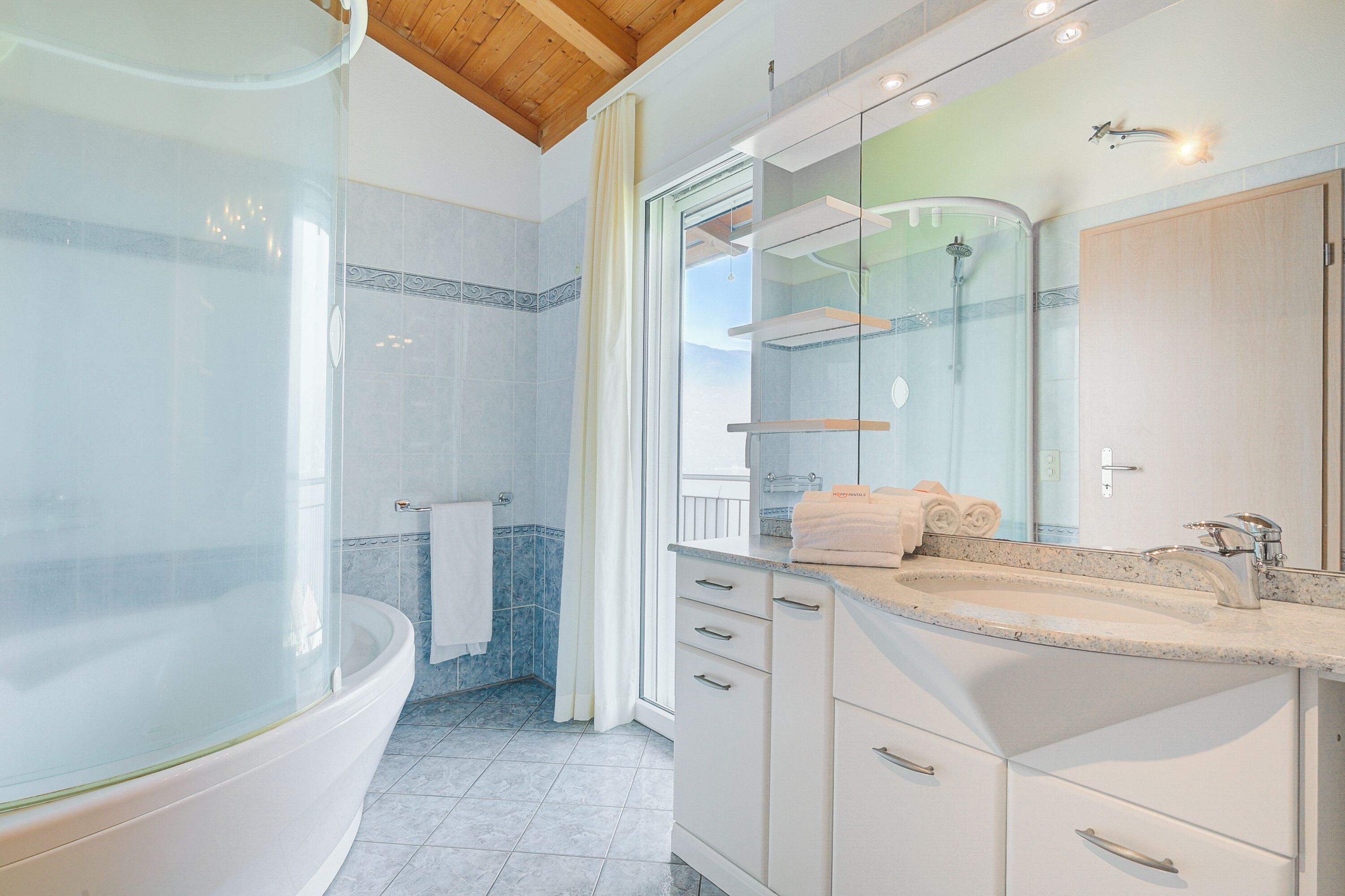 A modern bathroom with a freestanding bathtub, a glass-enclosed shower, and a vanity with a mirror.