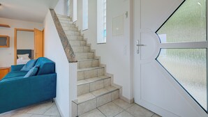 Eine Treppe führt zu einem Schlafzimmer mit einem blauen Sofa und einem Bett.