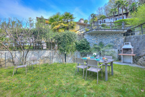 A patio with a table and chairs, a grill, and a stone wall.