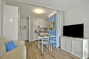 A compact living space with a kitchenette, dining area, and a flat-screen TV.