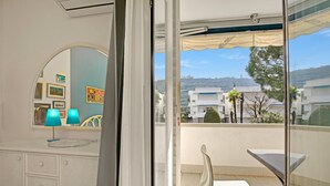 A balcony with a table and chairs, a view of buildings, and a mirror reflecting the room. - Garden & Surf Residenza By Max With Pool & Balcony (Riva del Garda)