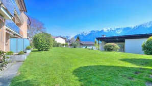 A well-maintained grassy courtyard with a clear view of snow-capped mountains in the background. - Casa Miramonti Muralto With Garage and Garden (Muralto)