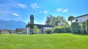 A house with a well-maintained lawn, a mountain in the background, and a clear sky. - Casa Miramonti Muralto With Garage and Garden (Muralto)