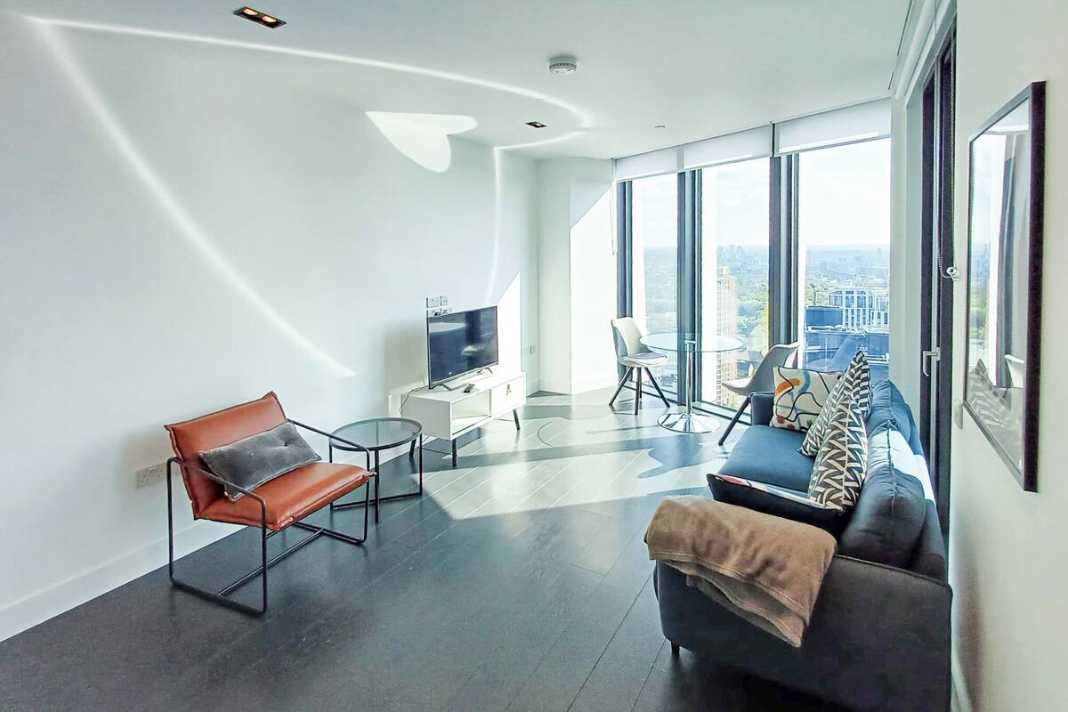 Un salon moderne avec un canapé, un fauteuil, un téléviseur et une table.
