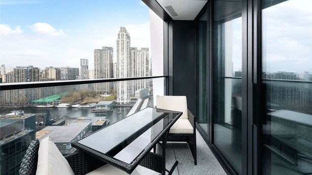 A modern balcony with a glass table and chairs, offering a city view. - One Bedroom Apartment City View (London)