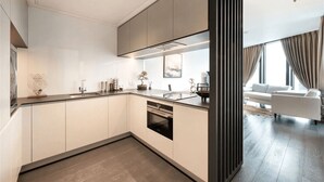 A modern kitchen with a central island, built-in appliances, and a dining area with a sofa and curtains. - One Bedroom Apartment City View (London)