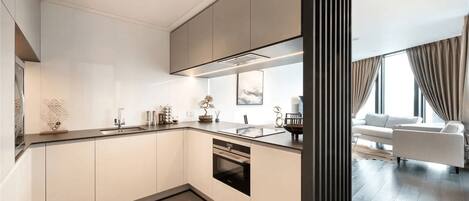 A modern kitchen with a central island, built-in appliances, and a dining area with a sofa and curtains.