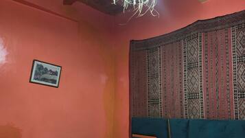 Un dormitorio con techo de madera, cabecera estampada, cama con ropa de cama floral y un cuadro en la pared.