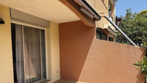 Un balcon doté d’un sol carrelé, d’une porte-fenêtre coulissante et d’un mur à texture.