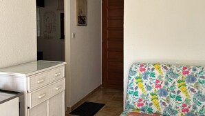 Une pièce avec un lit, une commode, une porte et un mur orné d’un tableau.
