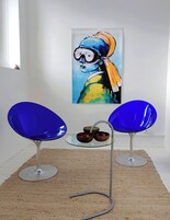 Dos sillas azules con una mesa de vidrio en el medio, un cuadro en la pared y una ventana con vistas.