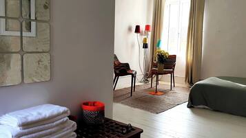 A hotel room with a bed, a desk with a lamp, a chair, and a wall with a mirror.