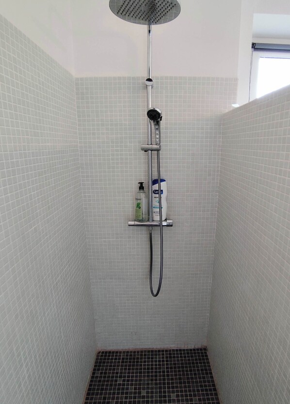 A shower with a handheld showerhead, a handheld shower attachment, and a handheld scrubber.