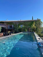 Una piscina con agua cristalina, rodeada por una terraza con sillas y una mesa.