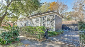 A single-story house with a garage, surrounded by a fence and trees. - Walkable & Historic Houston Heights Bungalow! (Houston)