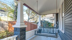 A porch with a swing, white railings, and a stone pillar. - Walkable & Historic Houston Heights Bungalow! (Houston)