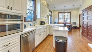 A spacious kitchen with white cabinetry, stainless steel appliances, and a wooden floor. - Walkable & Historic Houston Heights Bungalow! (Houston)