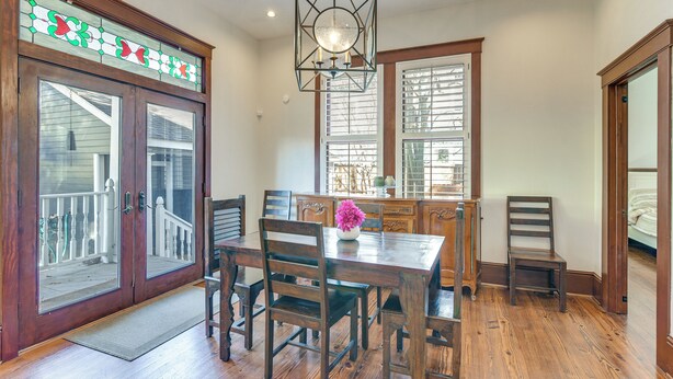A dining area with a wooden table, chairs, and a hanging light fixture. - Walkable & Historic Houston Heights Bungalow! (Houston)