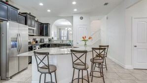 A modern kitchen with a central island, stainless steel appliances, and bar stools.