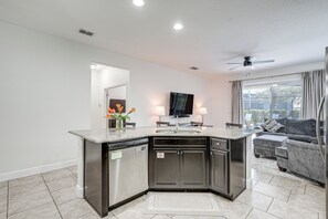A modern kitchen with a built-in island, stainless steel appliances, and a flat-screen TV above the island. - 10 Mi to Wdw: Family Home w/ Game Room & Pool! (Davenport)