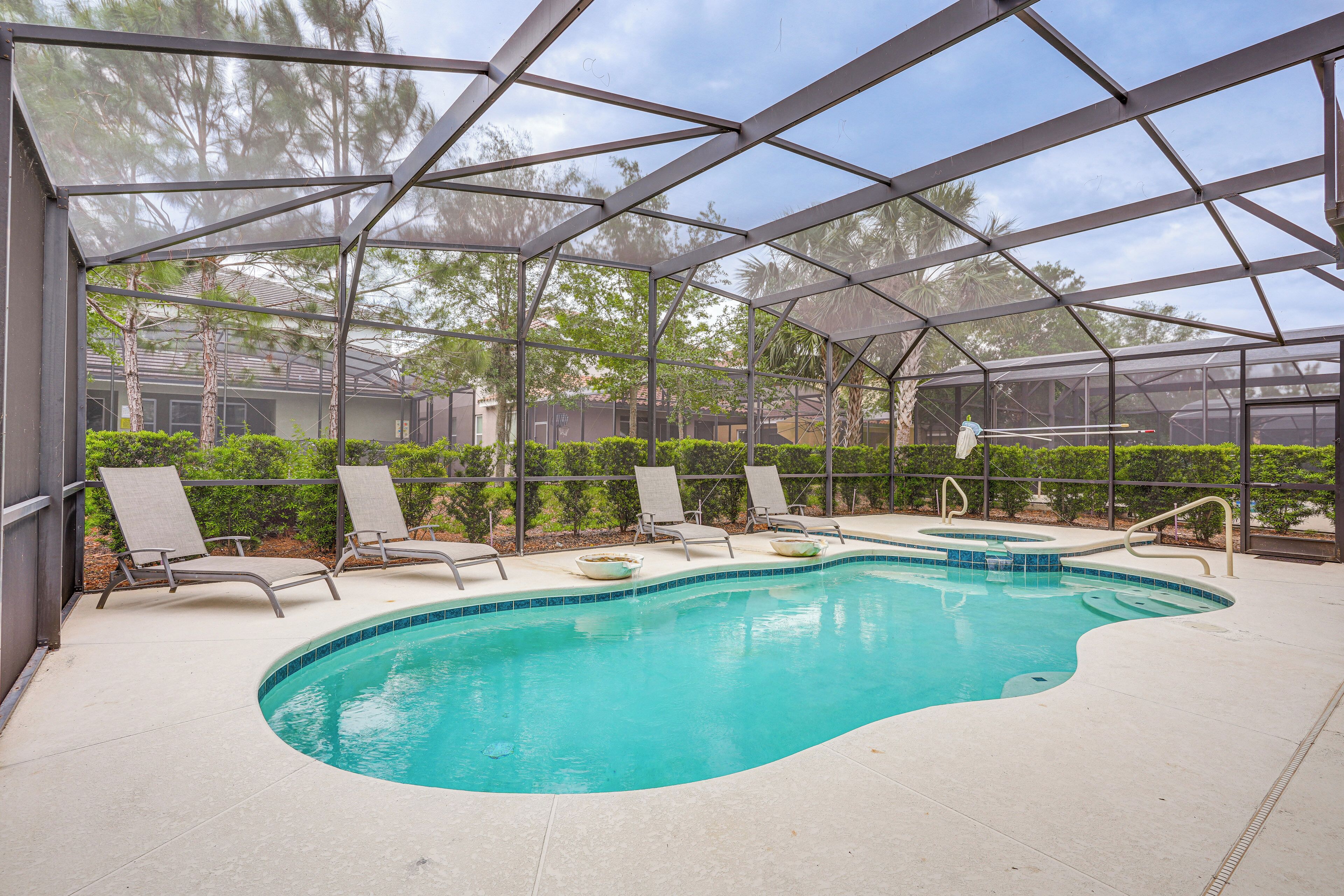 A covered swimming pool with lounge chairs and a hot tub.