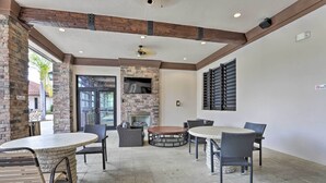 An outdoor patio area with stone flooring, round tables, and wicker chairs.