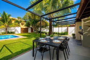 An outdoor dining area with a pool, surrounded by palm trees and a clear sky. - Bz04 30 passos da praia casa piscina (Buzios)