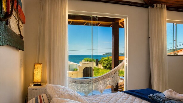 Un dormitorio con una cama grande, una hamaca y vista al mar.