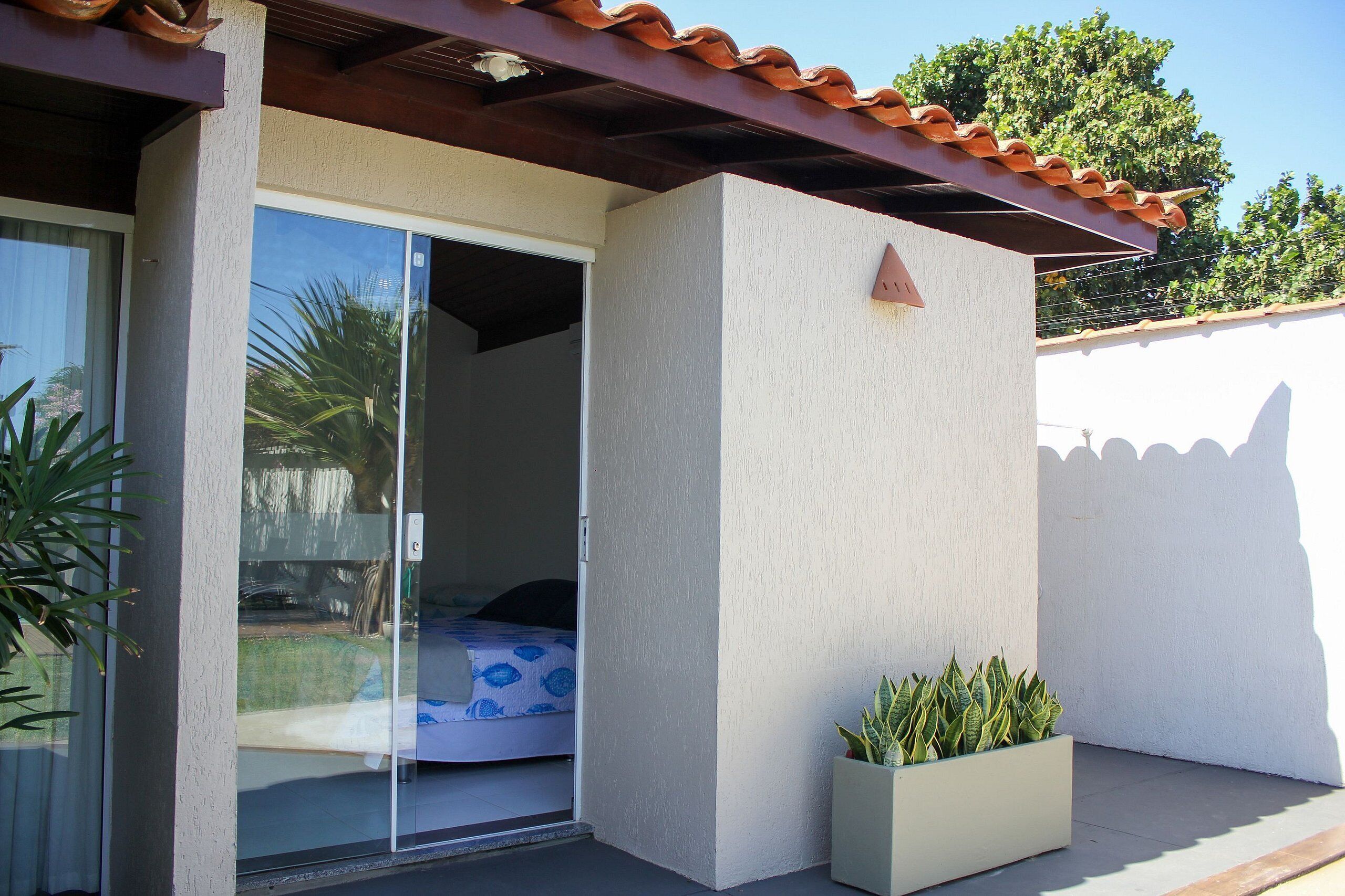 A room with a bed, a sliding glass door, a small planter with plants, and a tiled roof.