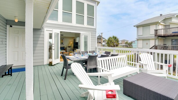 Une terrasse extérieure couverte, aménagée avec une table et des chaises, un banc et un canapé en osier.