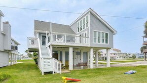 Une maison à deux étages avec un balcon, une véranda et un petit jardin à l’avant.