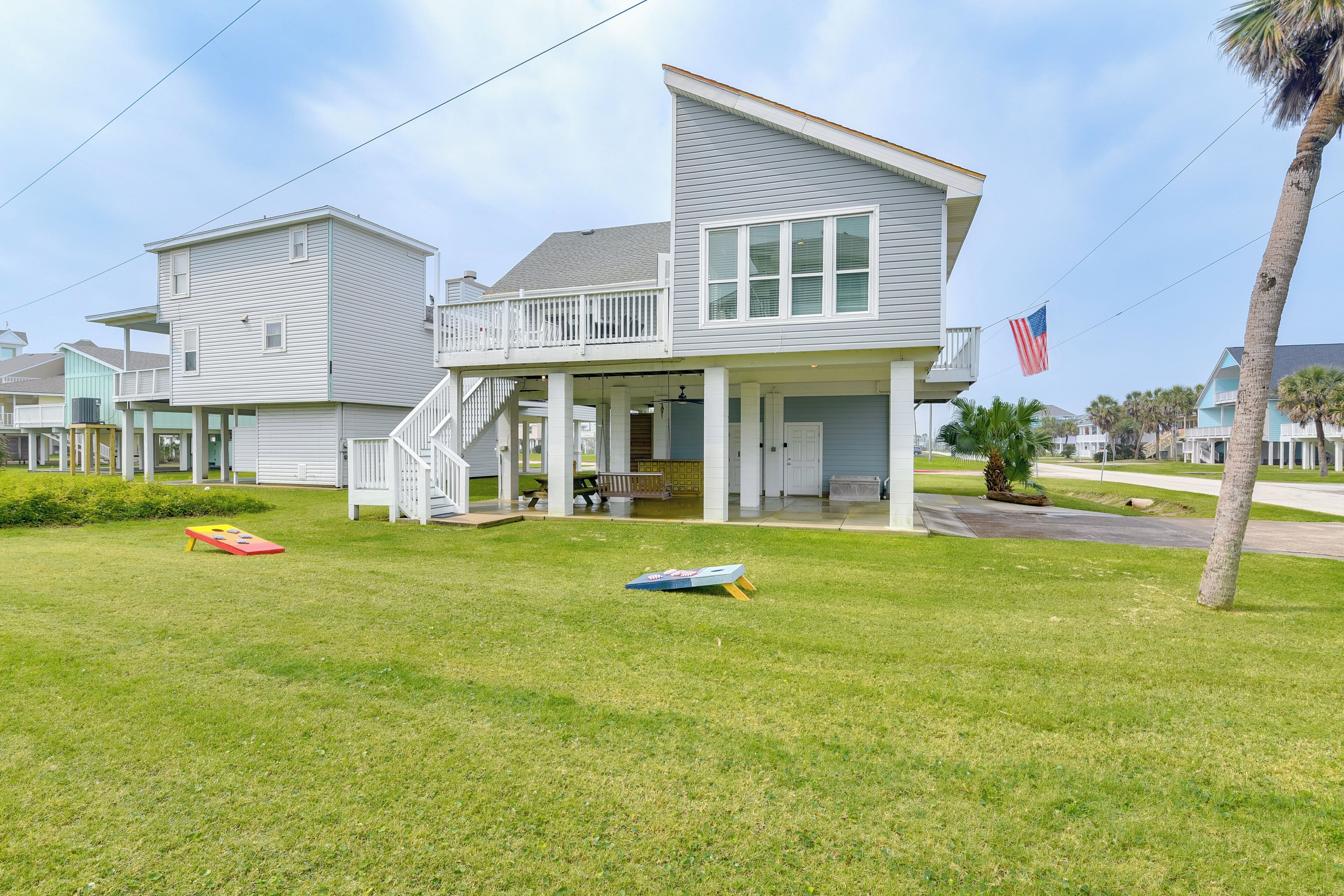 A two-story house with a balcony, a flag, and a lawn with a frisbee.