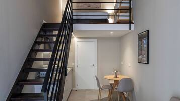 Un interior moderno con una escalera, un sofá, una mesa de comedor y un techo de listones de madera.