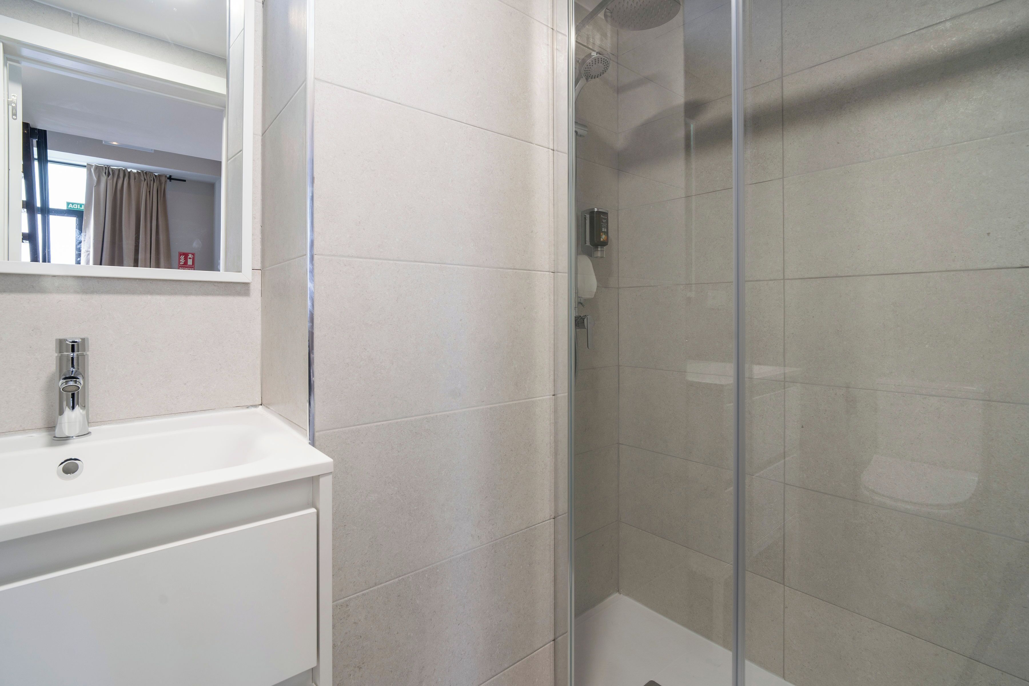 Un bagno moderno con doccia vetro, lavandino bianco e specchio sopra.