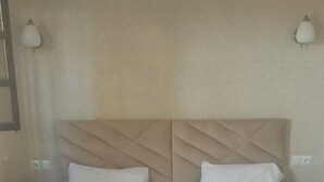 A hotel room with a large bed, two pillows, a brown blanket, and two bedside lamps. - Hôtel de la paix (Marrakech)