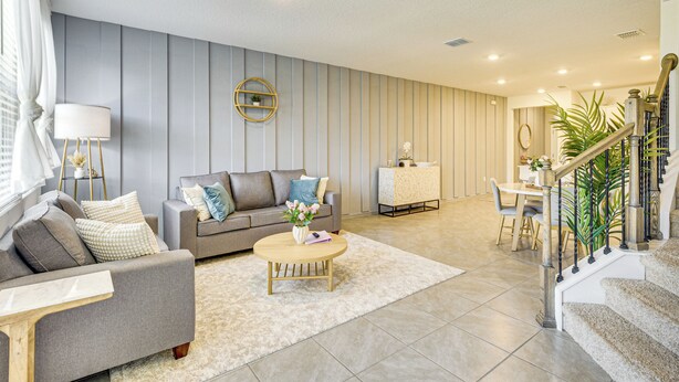A modern living room with a grey sofa, a round coffee table, and a staircase leading to an upper floor. - 7 Mi to European Village: Pond-front Townhome! (Palm Coast)