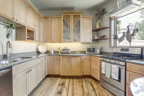 A kitchen with wooden cabinets, a stainless steel sink, a microwave, a stove, and a window with a view of two roosters. - Walkable Apt in Carbondale: 'luxury Artist's Loft' (Carbondale)