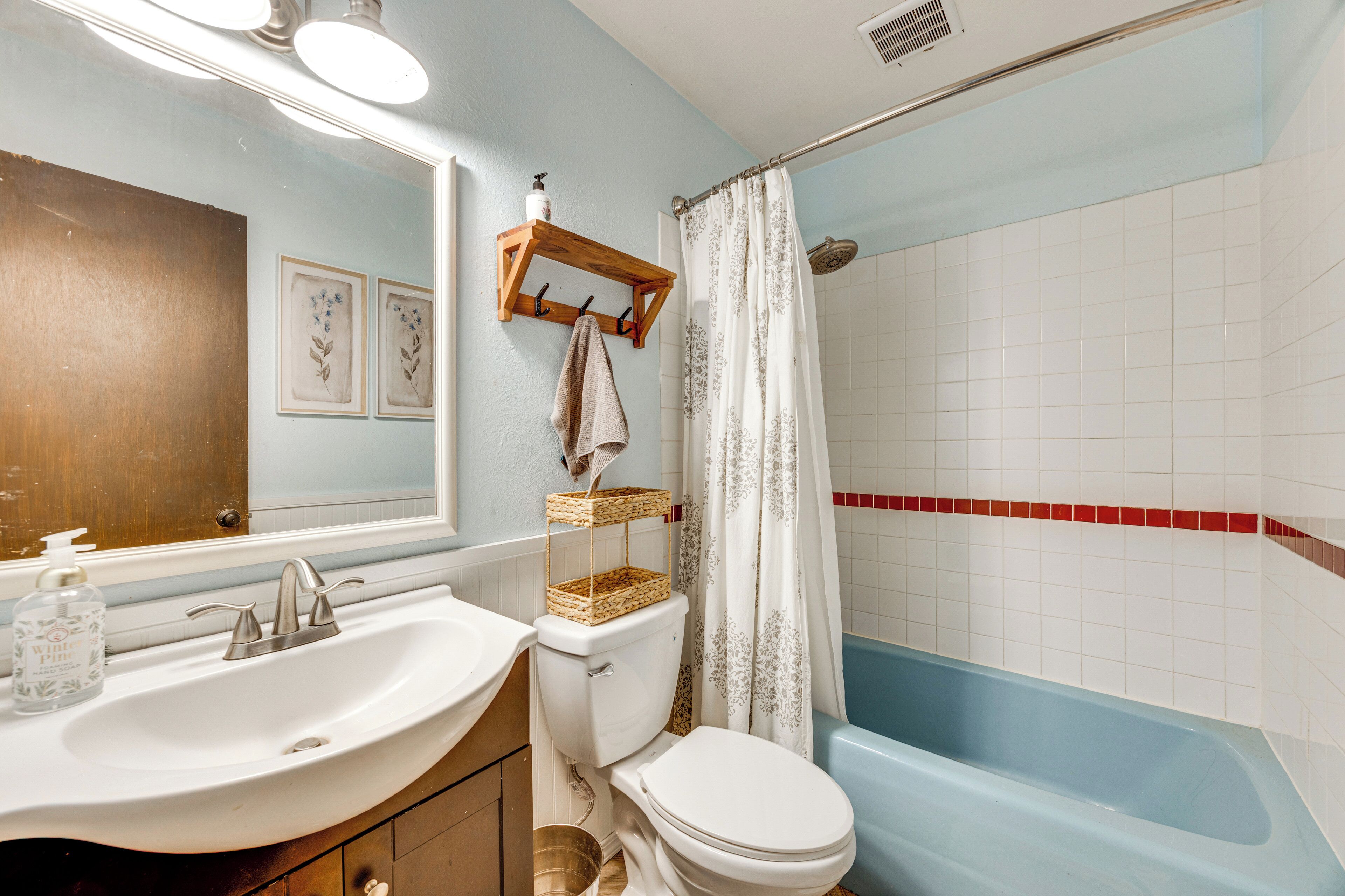 A bathroom with a white sink, a toilet, a bathtub, and a shower curtain.
