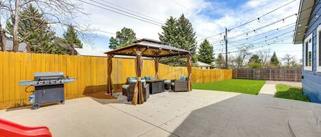 A backyard with a barbecue area, outdoor seating, and a slide.