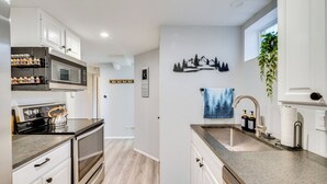 A modern kitchen with white cabinets, stainless steel appliances, and a granite countertop.