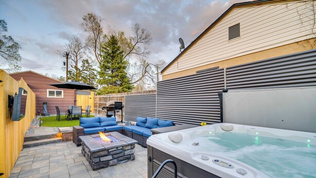 A backyard with a hot tub, outdoor seating, and a fire pit.