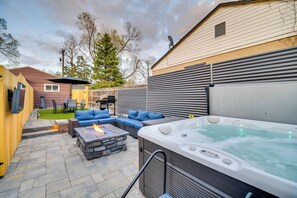 Un jardin avec un jacuzzi, un espace salon extérieur et un foyer.
