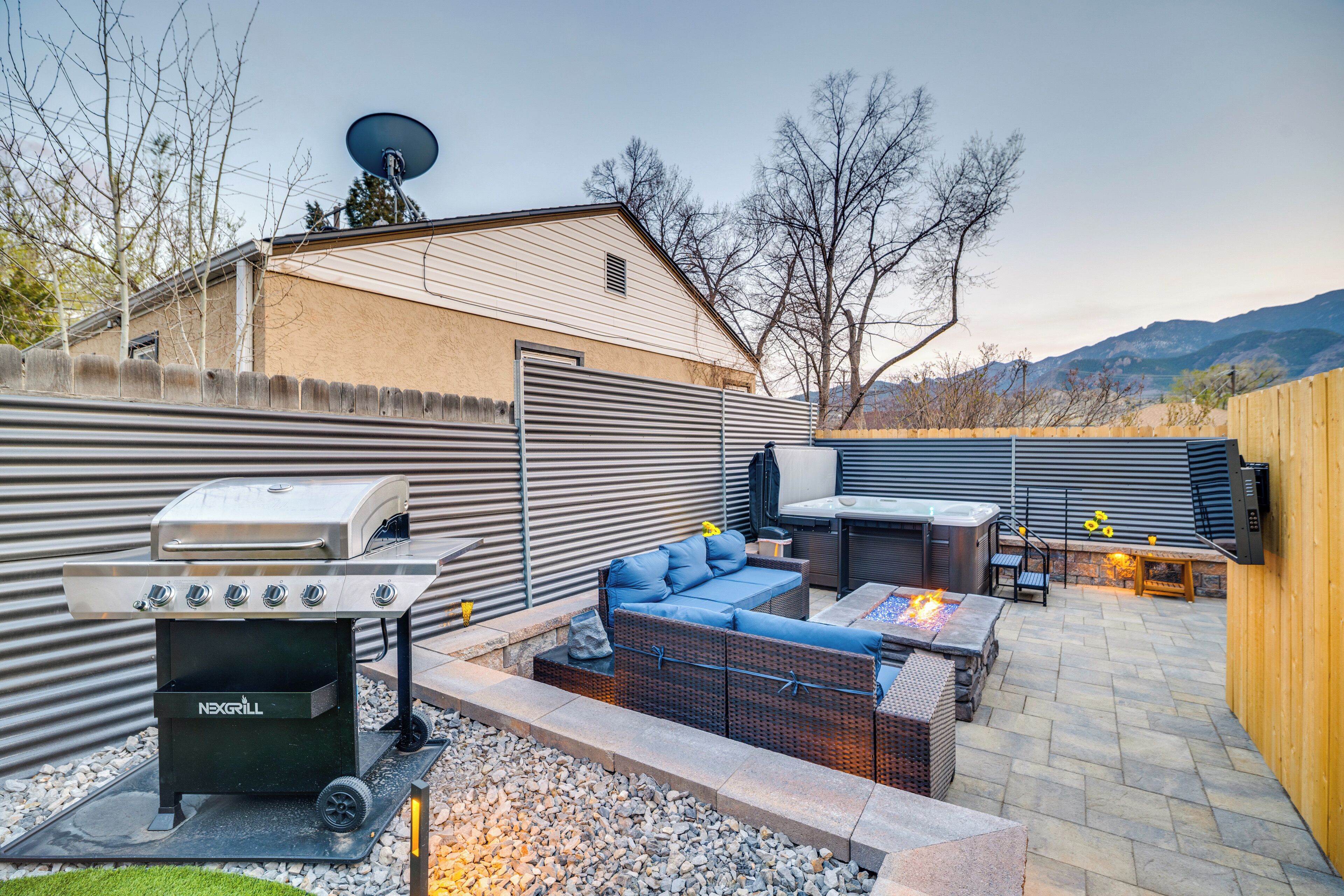 Un jardin avec un barbecue, un espace salon et un foyer extérieur.