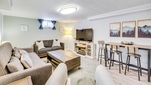 A modern living room with a sofa, coffee table, and bar stools.