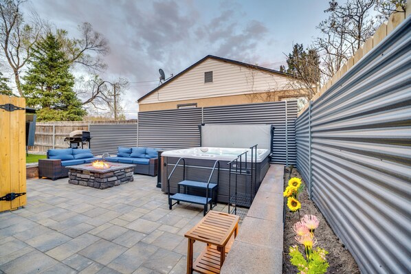 Un jardin avec un jacuzzi, un foyer extérieur, un espace salon extérieur et une terrasse en bois.