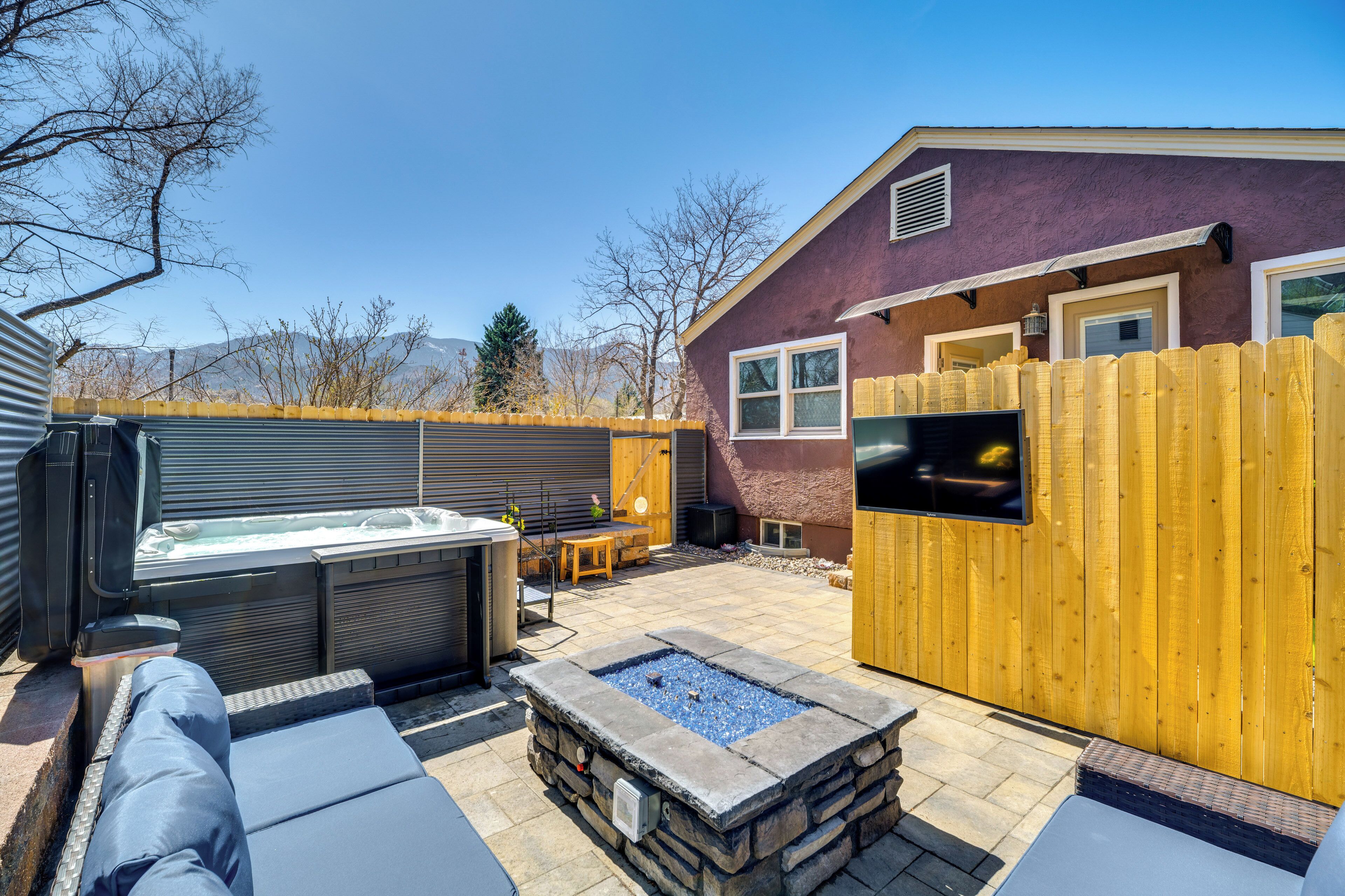 Un jardin avec un jacuzzi, un foyer en pierre et un espace salon extérieur.